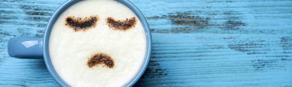 Coffee cup with a sad face design on a blue background